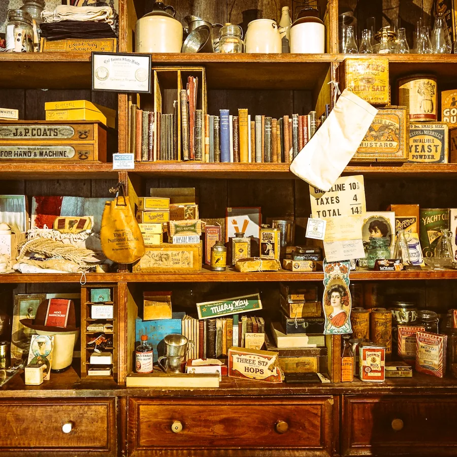 Wooden shelves packed with old books, frames, tins and curiosities