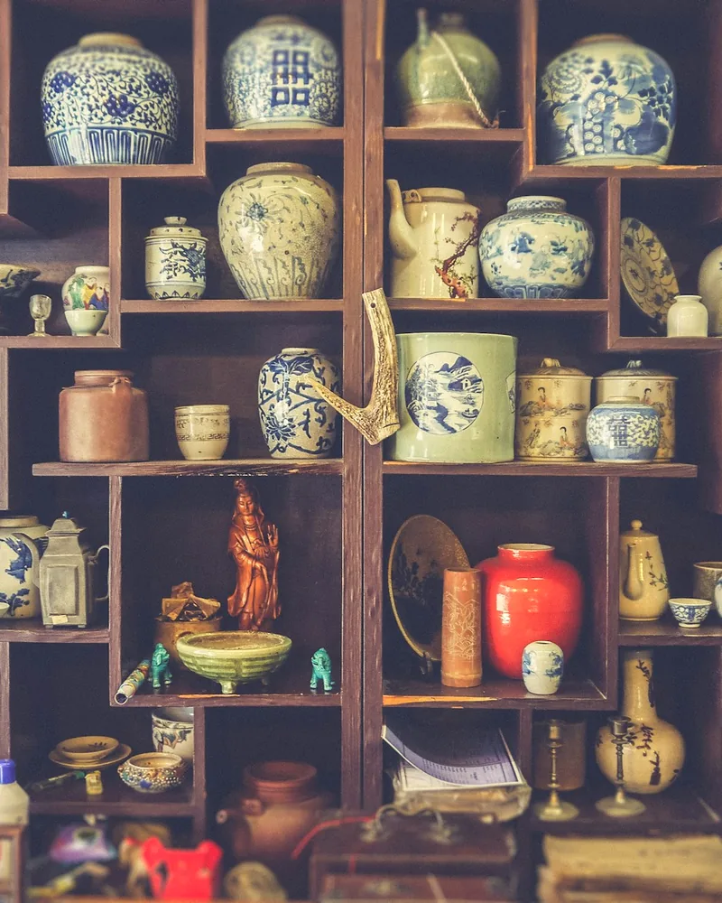 A wall of shelves filled with blue-and-white porcelain jars and curios